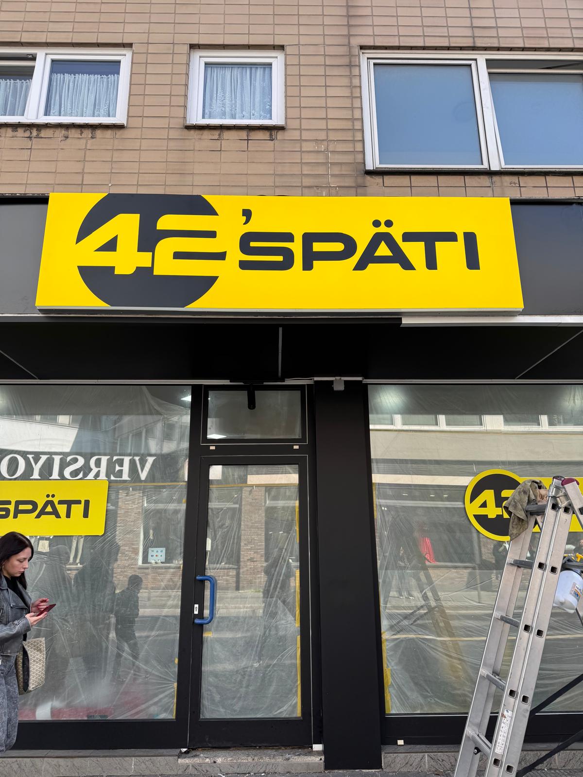 LED-Leuchtkasten von 42’späti am Kipdorf in Wuppertal mit gelb-schwarzem Digitaldruck