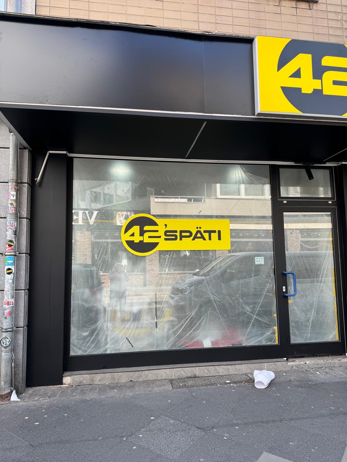 Schaufensterbeschriftung von 42’späti in Wuppertal mit Logo und mattschwarz folierten Rahmenprofilen