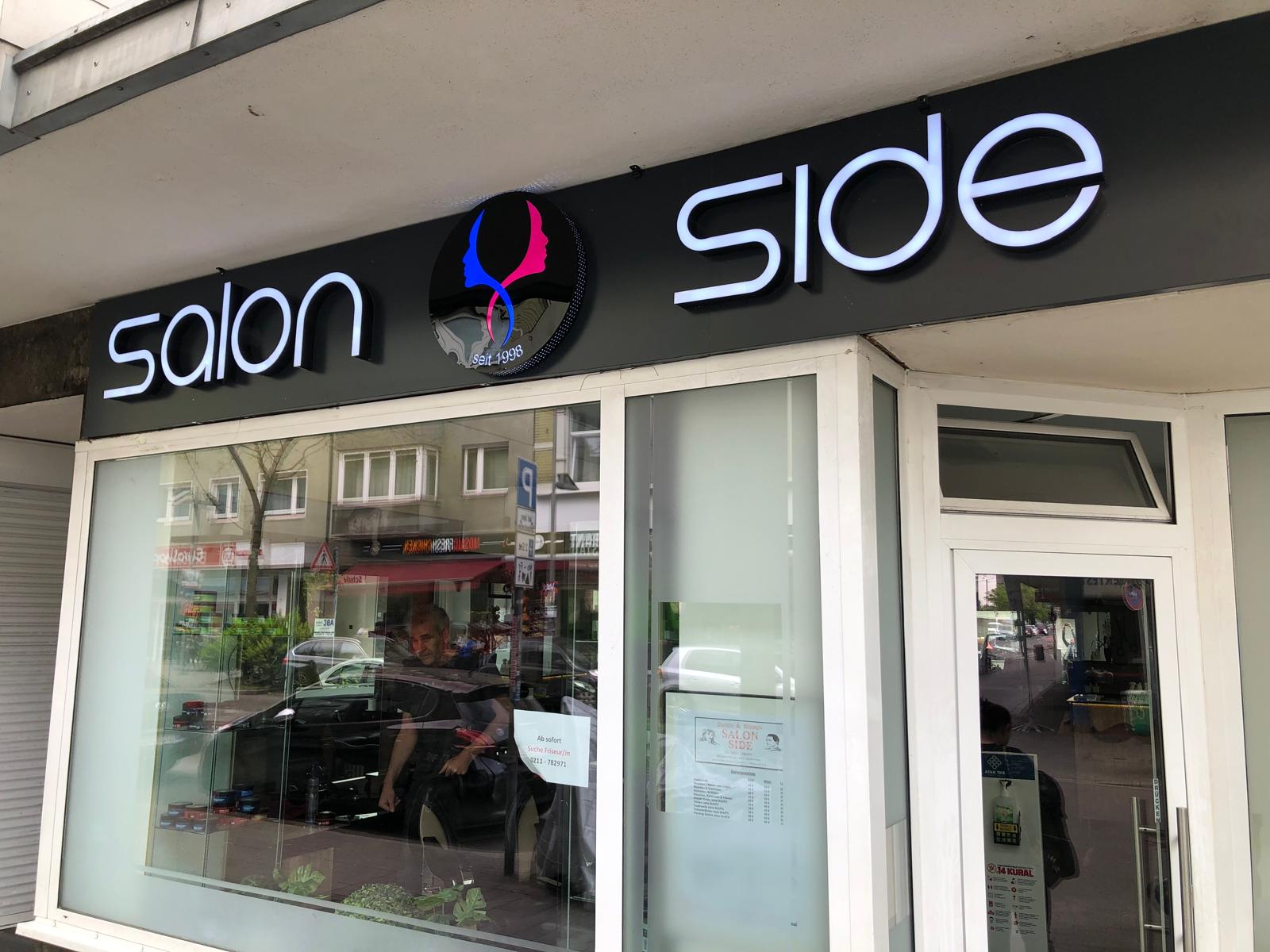 Salon Side, Düsseldorf Kölner Straße: Beleuchtet – Detailansicht der LED-Buchstaben und des runden Acryllogos.